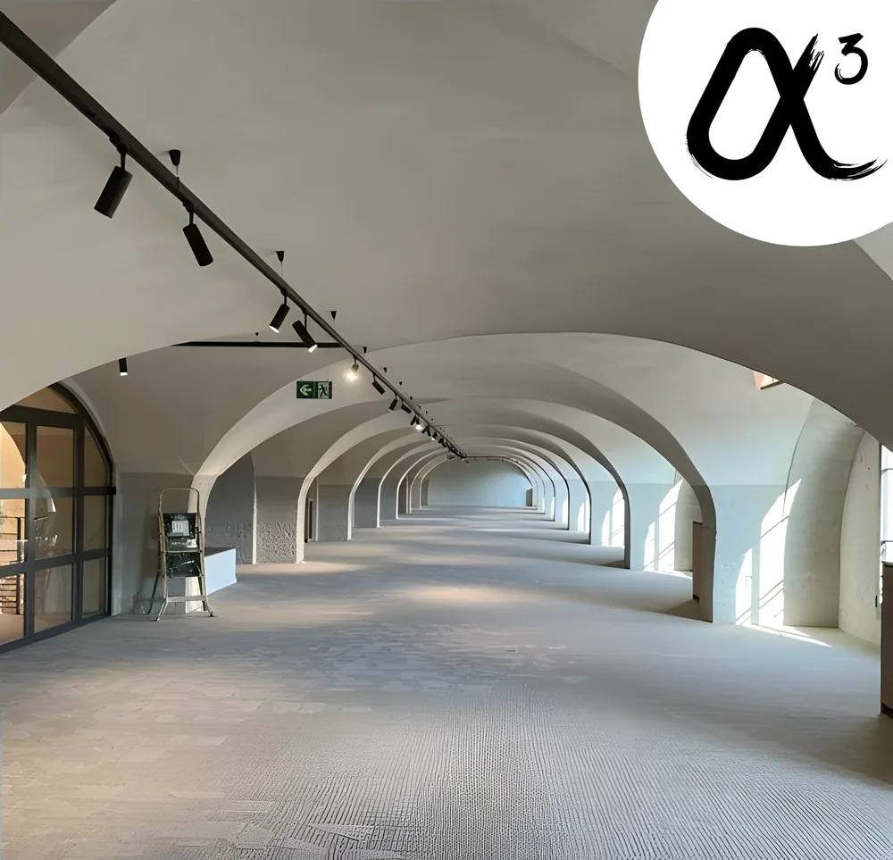 Longue galerie voûtée aux murs clairs, éclairée par un rail de spots